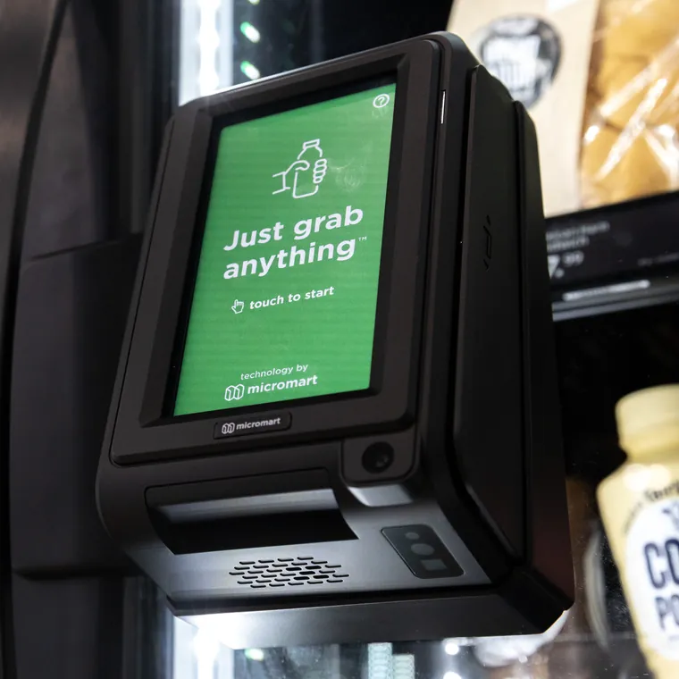 Touchscreen checkout on the cooler door reading Just grab anything, touch to start