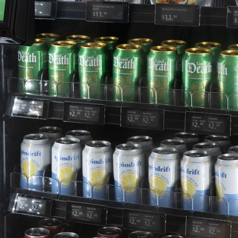 Rows of canned drinks with small digital price tags on each shelf edge